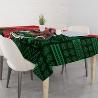 Green geometric tablecloth with red floral accents, hanging edge over dining table
