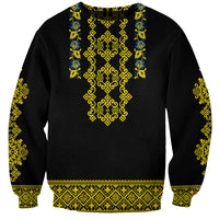 Black sweatshirt with gold, blue, and green Ukrainian folk pattern at center and cuffs