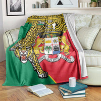 Leopard-pattern Benin coat-of-arms blanket draped over sofa, green, red, and yellow.