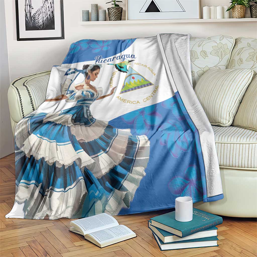 Blue Nicaragua fleece blanket draped over sofa, printed dancer and shield emblem