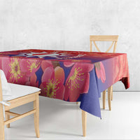 Red floral tablecloth with pink and purple blossoms draped over a dining table