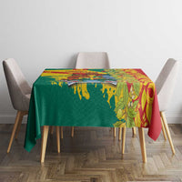 Tablecloth over dining table with green-and-yellow splatter edge and red leafy section