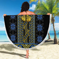 Round beach blanket held open, black folk motif center with blue gold designs and braided fringe