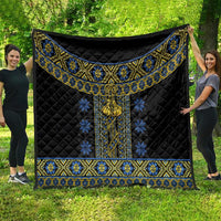 Black quilt blanket with blue and yellow folk pattern border and hanging tassel
