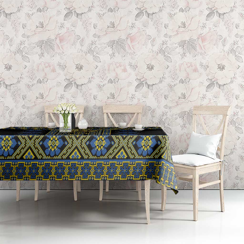 Black tablecloth with blue and yellow geometric folk design on long dining table.