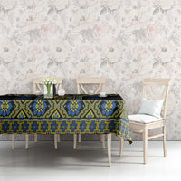Black tablecloth with blue and yellow geometric folk design on long dining table.