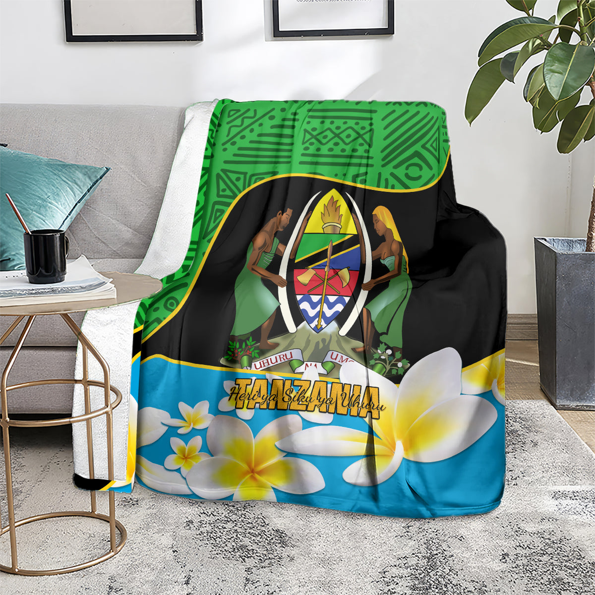 Green, black, and blue blanket with central crest emblem and plumeria flowers on a living room chair