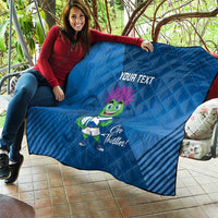 Blue quilt blanket held on a couch with 'YOUR TEXT' and green thistle mascot