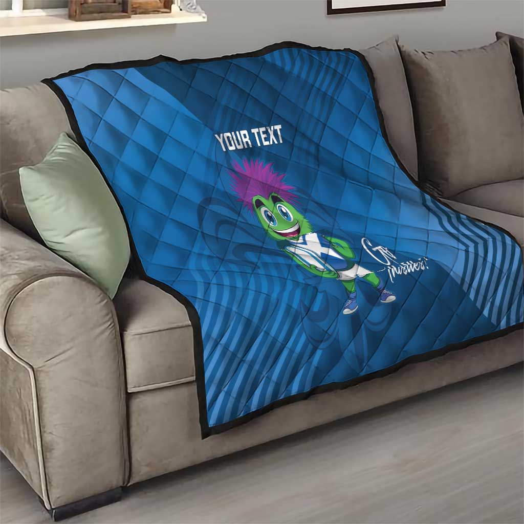 Blue quilt blanket on sofa with 'YOUR TEXT' and green thistle mascot image