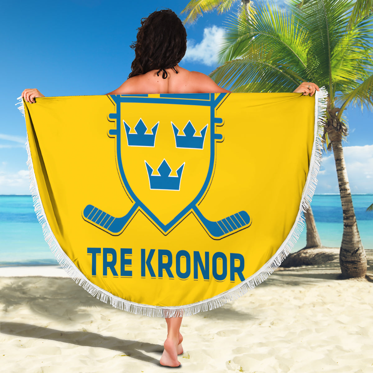 Yellow round beach blanket with fringe, Sweden crest and 'TRE KRONOR' on sandy beach