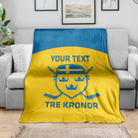 Sweden hockey blanket on sofa, yellow body with blue stripe, crest and “TRE KRONOR”