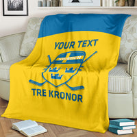 Sweden hockey blanket draped on couch, yellow with blue stripe, crest and “TRE KRONOR”