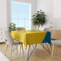 Yellow tablecloth with blue side stripe and crest, laid over dining table
