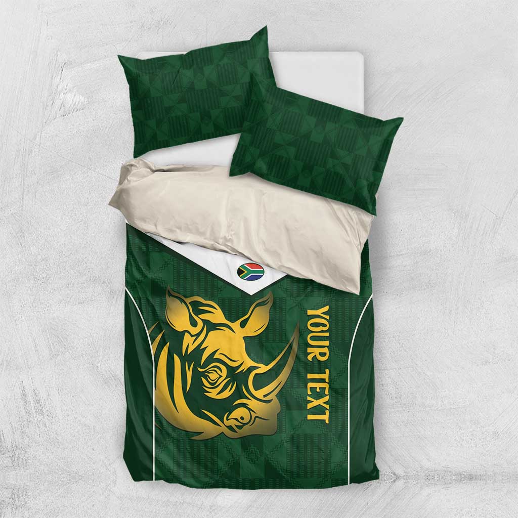 Green bedding set on white background: duvet with gold rhino face, yellow vertical text, shams