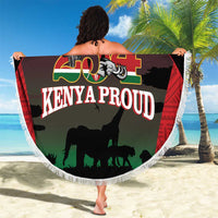 Round fringe beach blanket held outdoors, green/black safari animals and 'Kenya Proud' text