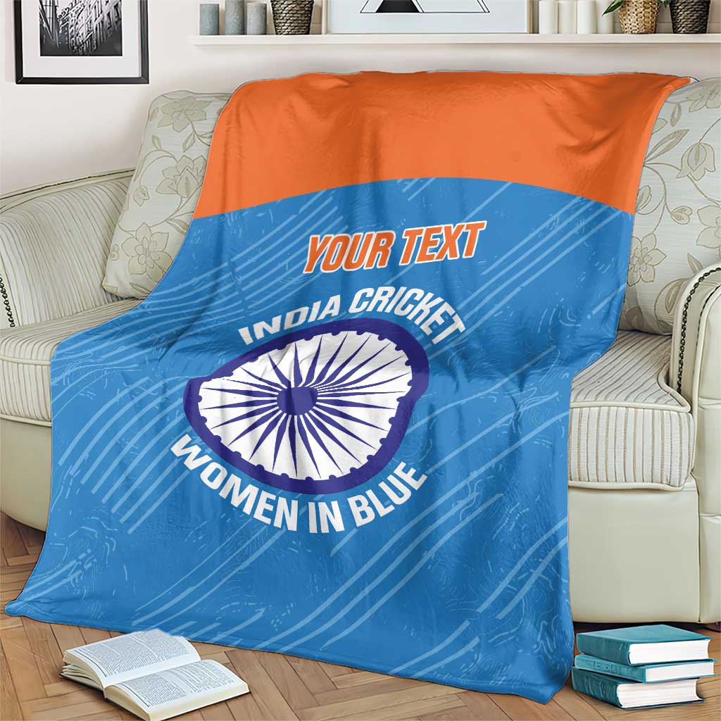 Blue cricket blanket with orange top band on couch, circular India Women in Blue emblem