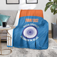 Blue cricket blanket with orange top band draped over chair, circular India Women in Blue emblem