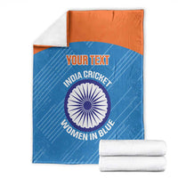 Blue cricket blanket with orange top band, circular India crest; folded with white towels