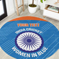 Blue round carpet with orange edge, central cricket emblem, printed “WOMEN IN BLUE”