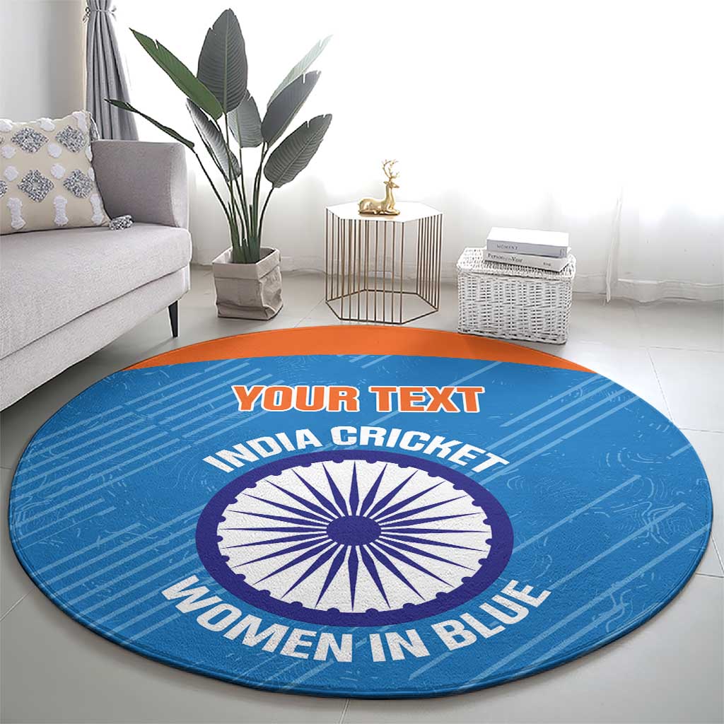 Blue round carpet with orange border, cricket emblem and “WOMEN IN BLUE” text