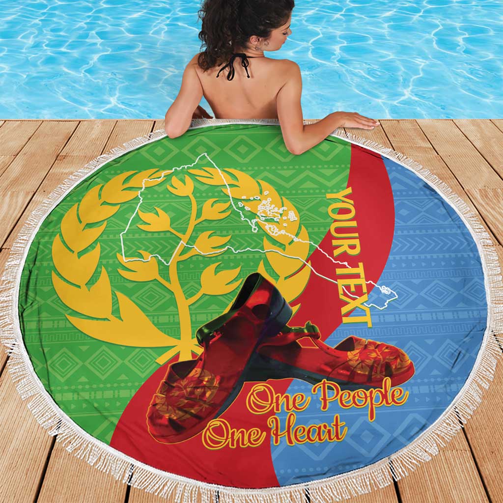Round beach blanket in green blue and red with white fringe, “One People One Heart”