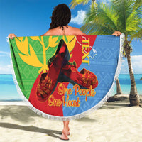 Round beach blanket with white fringe border in green blue and red, “One People One Heart”