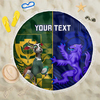 Round beach blanket with green left and blue right design, tassel fringe, bold emblem