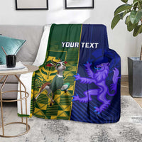 Rugby blanket folded on floor with green/blue designs, crest and lion, "YOUR TEXT"