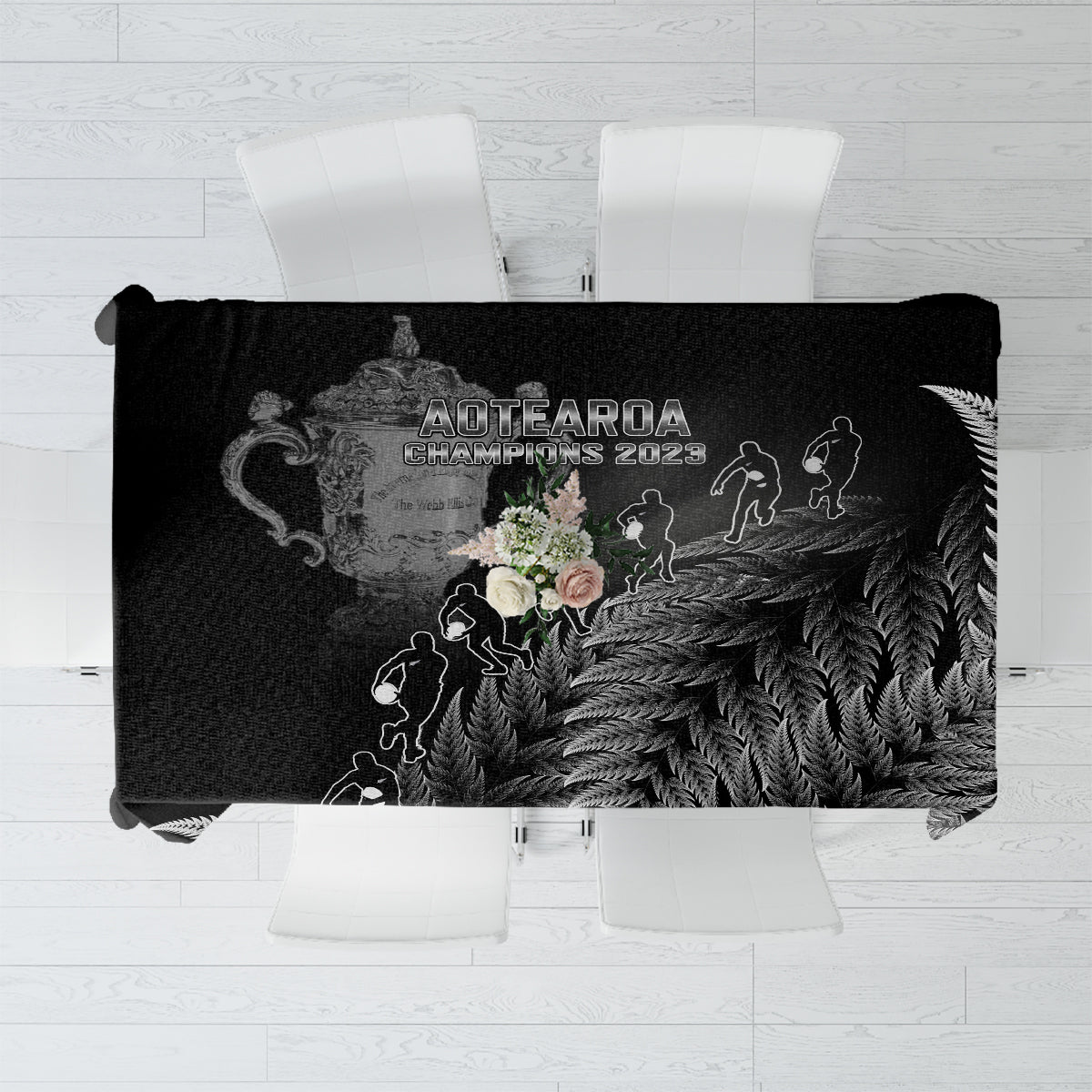 Black rectangular tablecloth with silver fern leaf pattern and trophy-style artwork