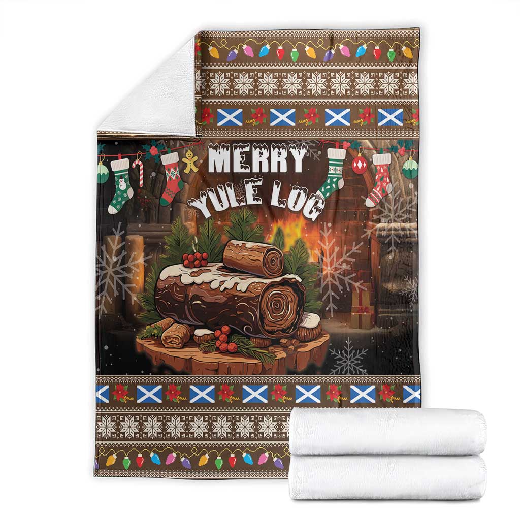 Folded Christmas blanket with “Merry Yule Log” print and multicolor border, with rolled white towels