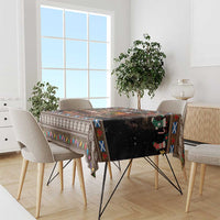 Christmas tablecloth on dining table, dark base with colorful patterned trim and holiday icons.