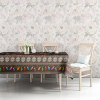 Christmas tablecloth on dining table, dark design with “Merry Yule” log artwork and colorful trim.