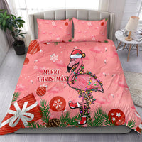 Pink bedding set on bed with two matching pillowcases, cartoon flamingo and “Merry Christmas”.