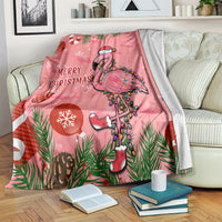 Pink flamingo Christmas blanket on bed with folds and “Merry Christmas” print