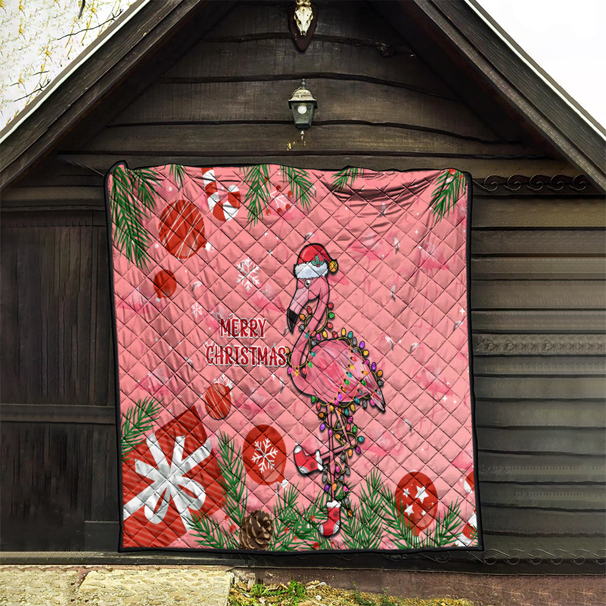 Pink flamingo holiday quilt hanging on a wooden wall with “Merry Christmas” text
