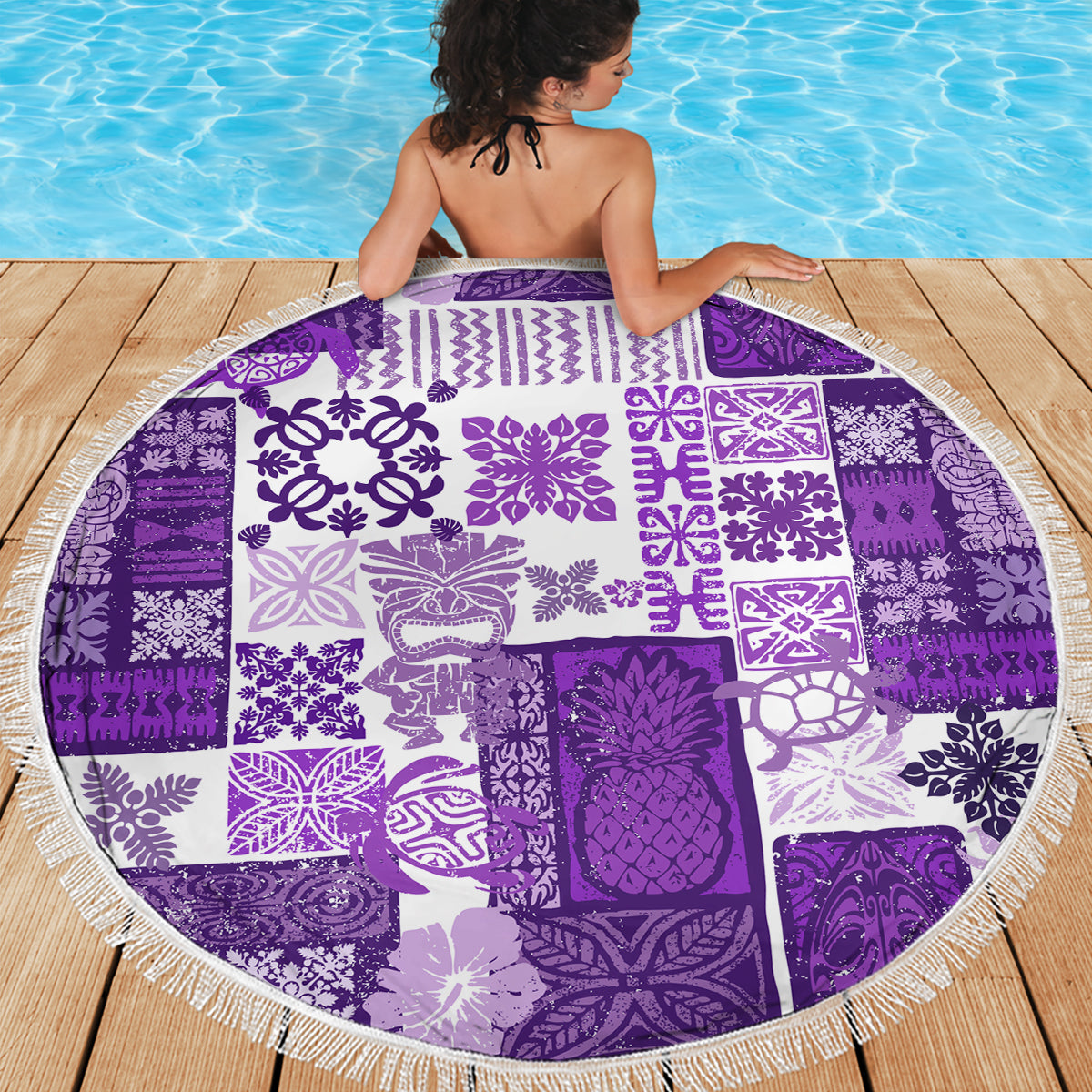 Purple and white round beach blanket showing bold tiki, leaf and geometric motifs with fringe