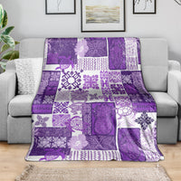 Purple tiki patchwork quilt blanket spread over a gray sofa, purple and white pattern