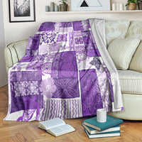 Purple patchwork tiki quilt blanket with purple and white designs, draped on armchair