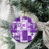 Purple quilt-pattern round ceramic ornament on tree branches with gold hanging loop