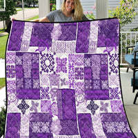 Purple and white patchwork quilt held up for a full view, square floral motif tiles