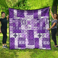 Purple and white quilt outdoors, patchwork square pattern with decorative floral prints