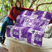 Purple and white quilt over a couch, patchwork blocks with floral designs