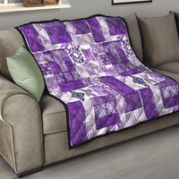 Purple and white quilt folded on a couch, patchwork squares with ornate floral motifs