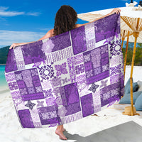 Purple patchwork quilt-style sarong with white tiki-inspired motifs, patterned border.