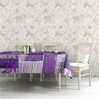 Purple quilt-style tablecloth on bench table with patchwork tiki motifs.