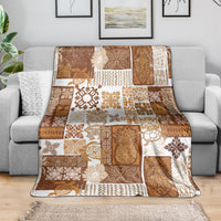 Brown and cream tropical quilt blanket draped over sofa, featuring tiki-style motif squares