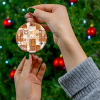 Brown quilt-style ceramic circle ornament held by hand with gold hanging string