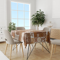 Brown quilt-style tablecloth with patchwork tiki motifs on dining table with chairs