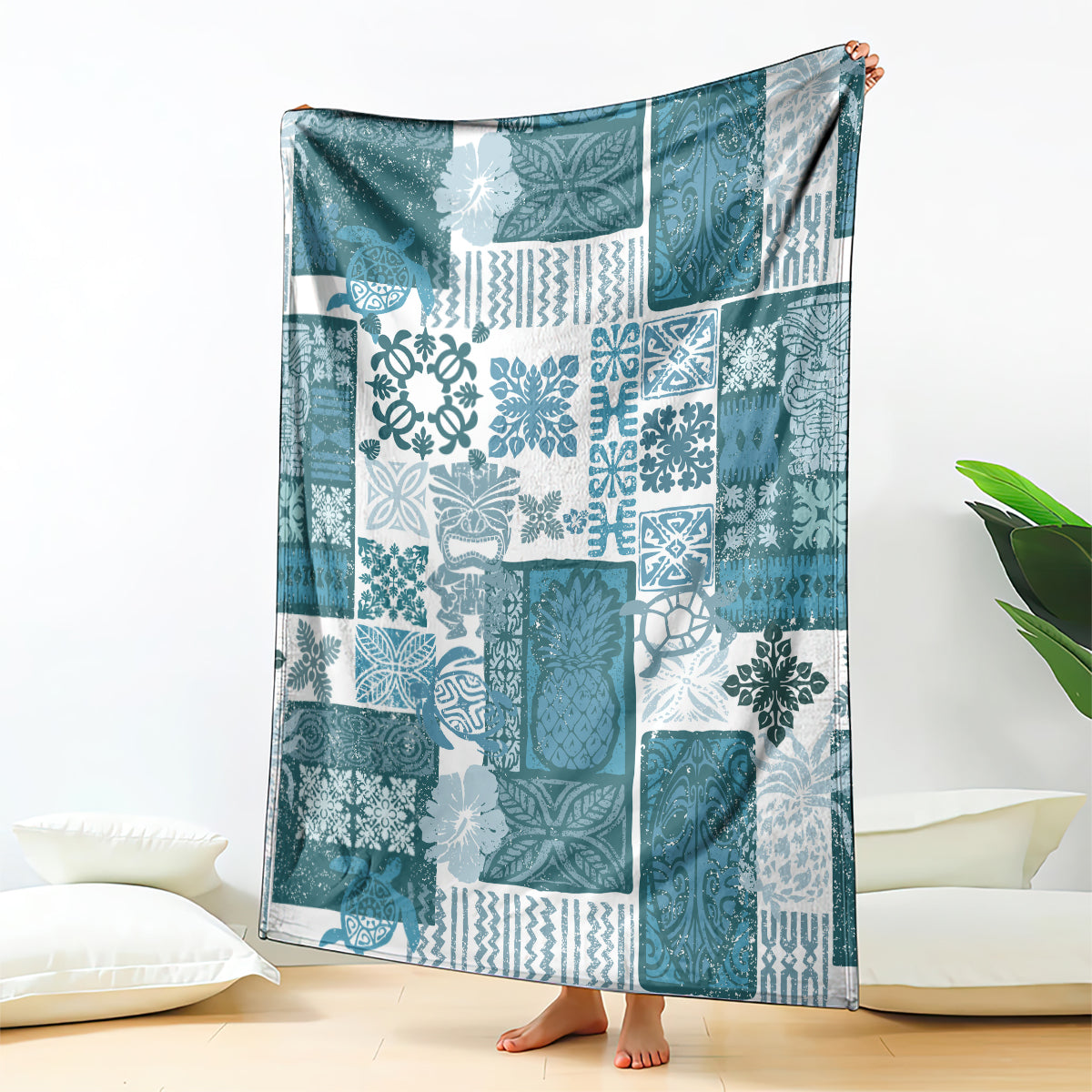 Dark cyan patchwork quilt blanket with white tiki motifs, scrolled patterns, and border trim