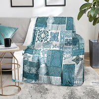 Teal patchwork quilt blanket with white tropical pattern squares and textured motifs